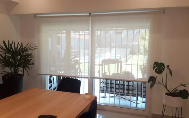 Cortina sun screen en un comedor diario con vista al jardín